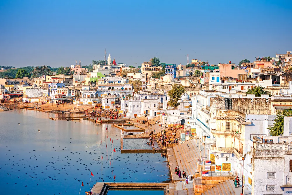 PUSHKAR, INDIA - NOVEMBER 20, 2012: Hindu pilgrims bathing in sacred Lake Pushkar (Sarovar) on ghats. Countless people in colourful attire gather to take a dip in the Holy Lake and pray to deities. 