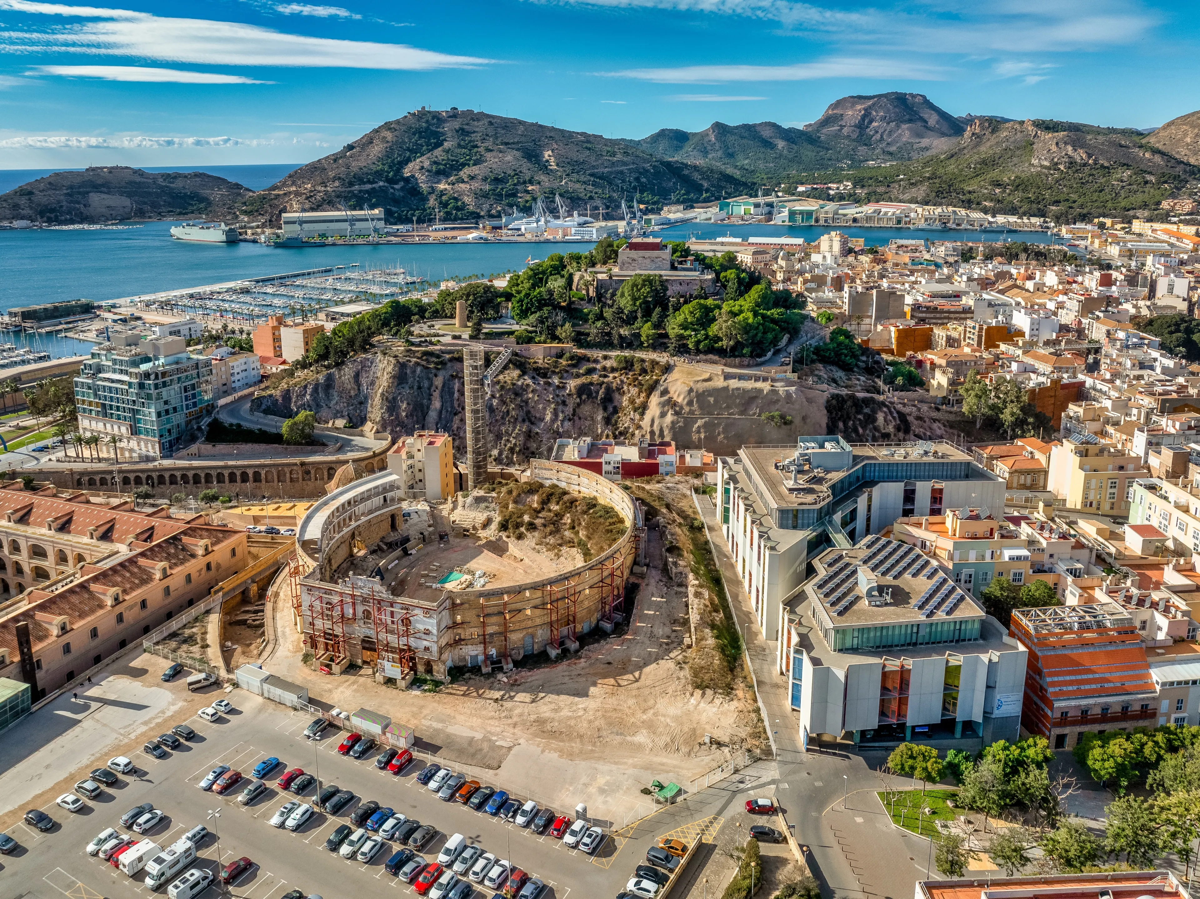 Aerial view of Cartagena port city in Spain surrounded by bastions and fortifications, medieval castle hill, roman amphitheater, bull ring, 