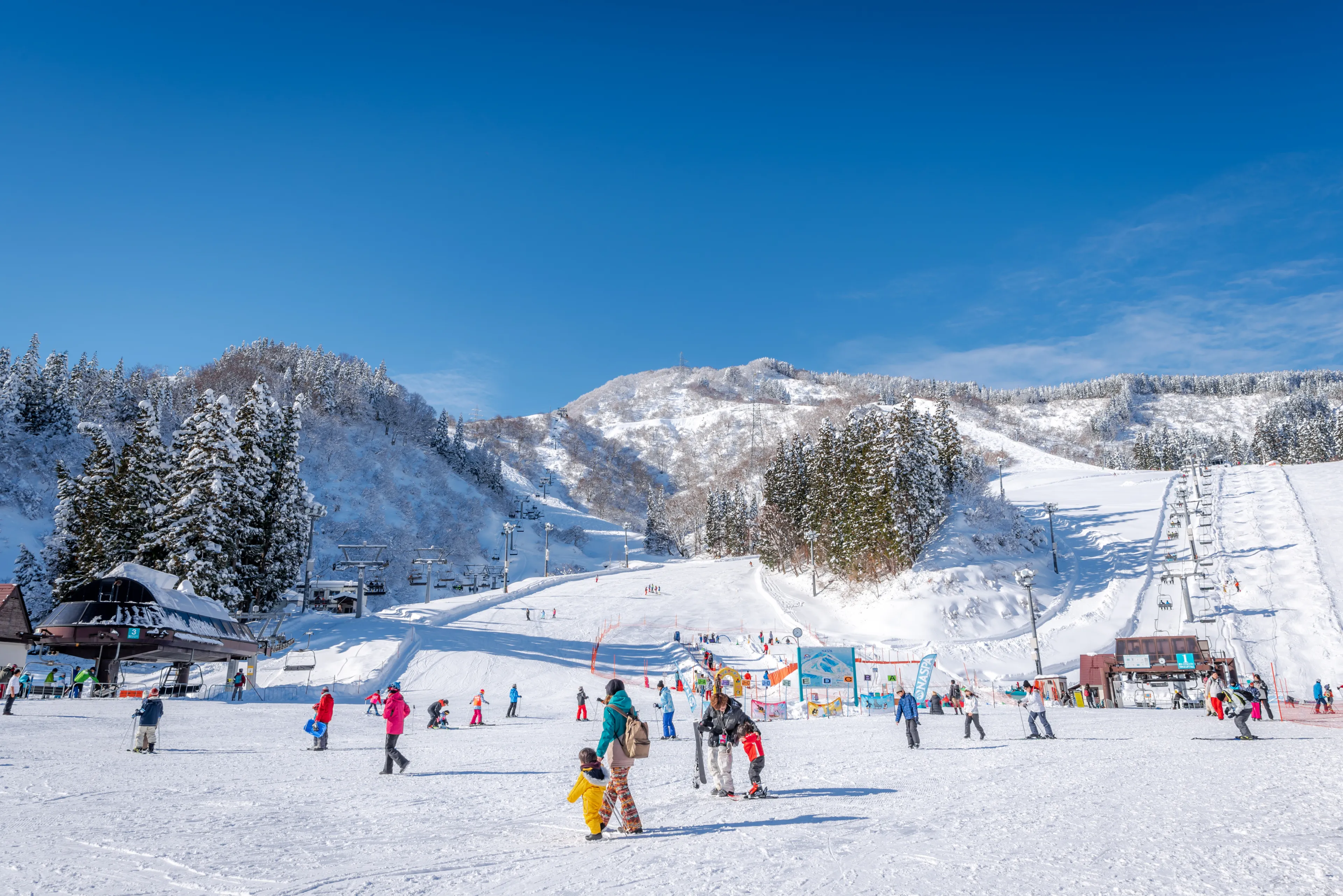 Minamiuonuma, Niigata, Japan, January 03, 2019 : People walking and skiing with mountains view in the background at NASPA Ski Garden in Yuzawa City.