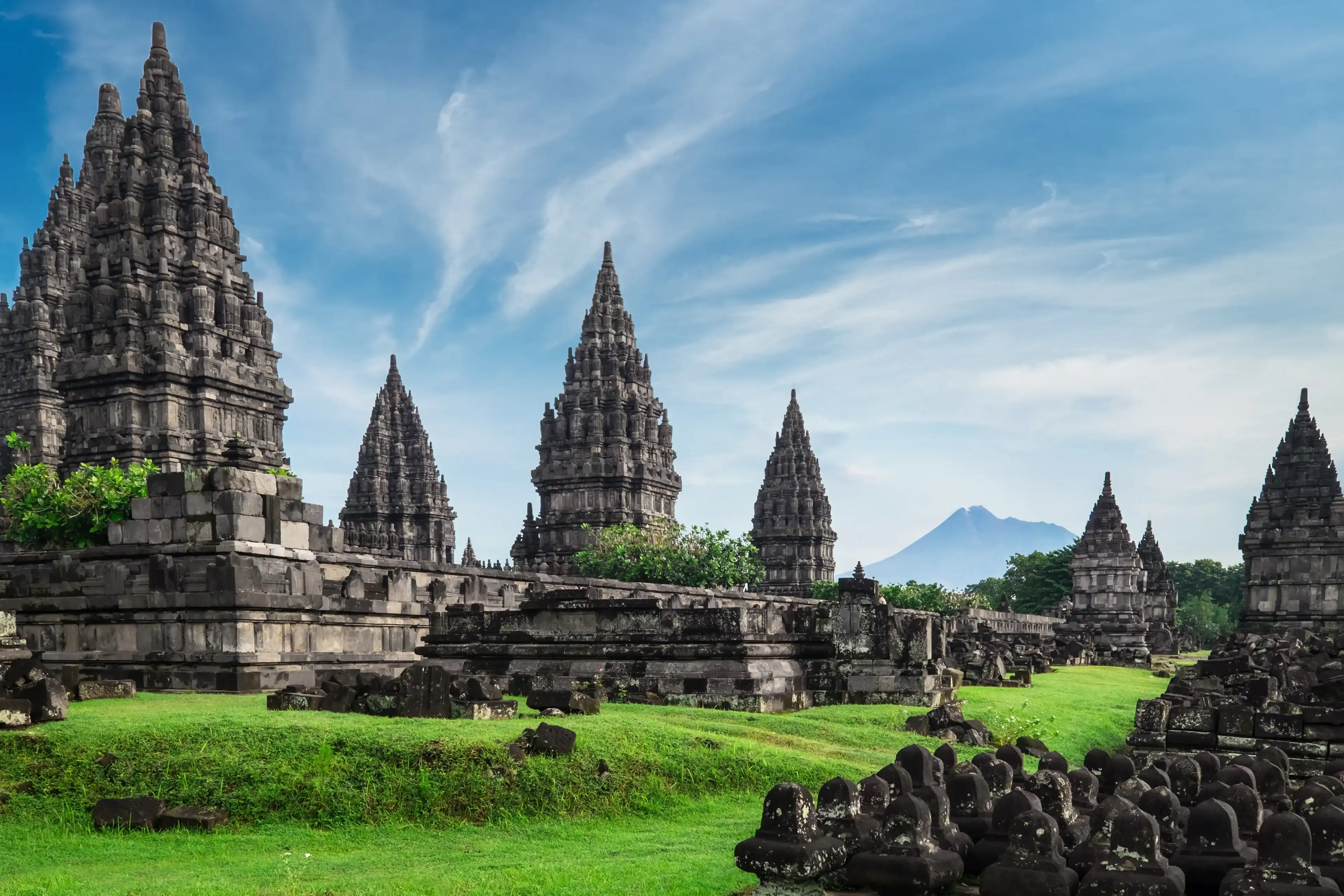 Ancient stone ruins on green field and Candi Prambanan or Rara Jonggrang, Hindu temple compound on background. Impressive architectural site. Yogyakarta, Central Java, Indonesia. Panoramic view. Ancient stone ruins on green field and Candi Prambanan or Rara Jonggrang, Hindu temple compound on background. Impressive architectural site. Yogyakarta, Central Java, Indonesia. Panoramic view.