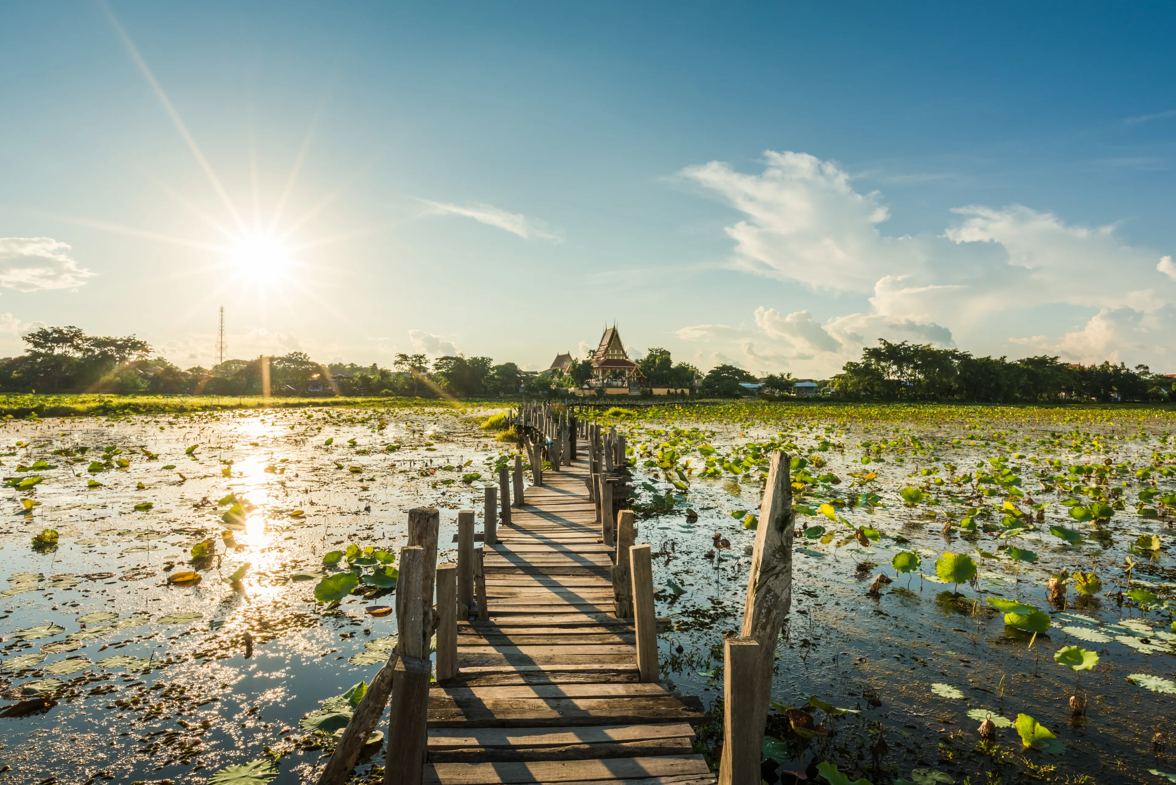 Long wooden bridge across the lake on sunset background at Kae Dam District, Maha Sarakham Province, Thailand