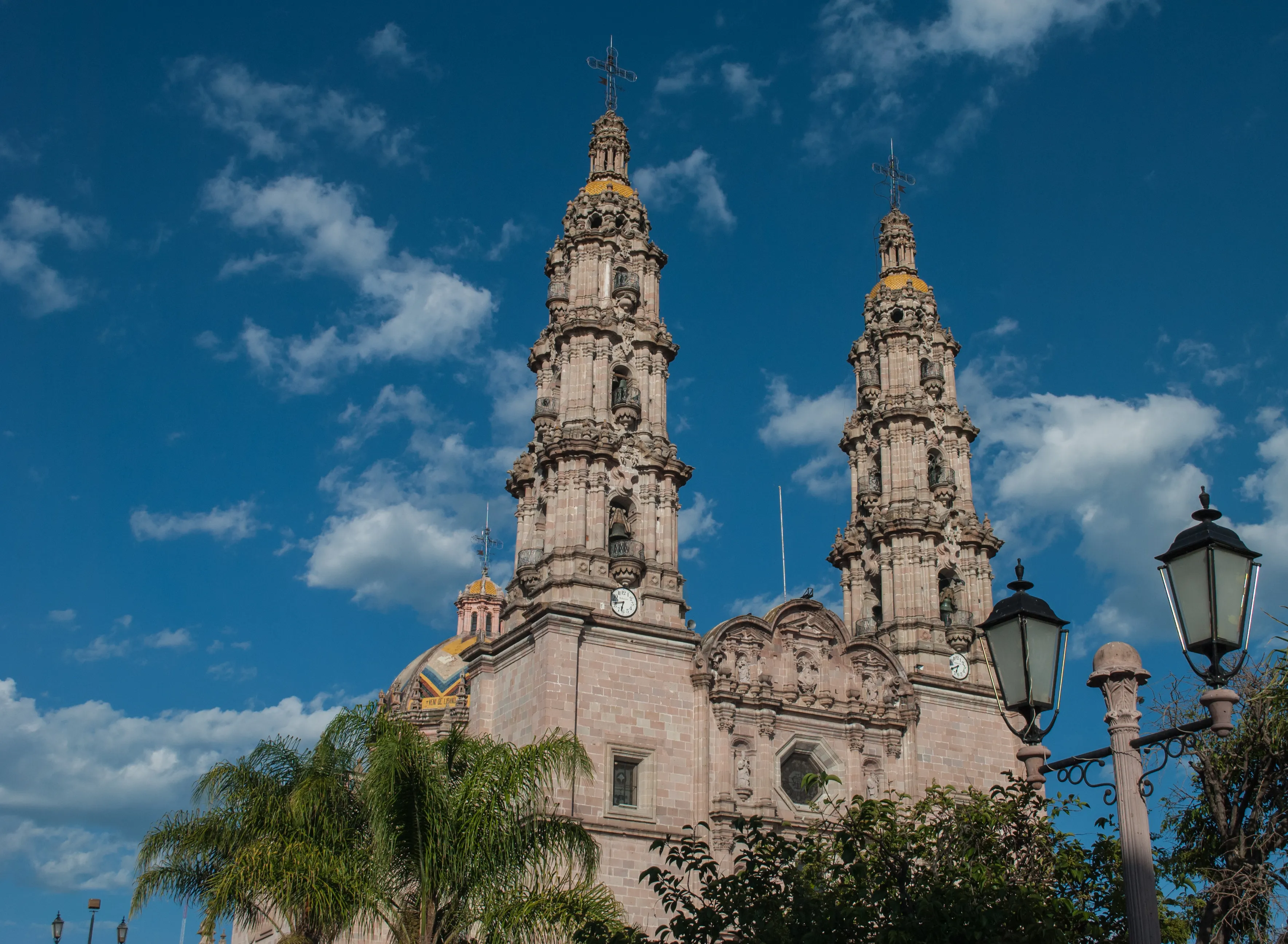 The Cathedral/Basilica of the Virgin of San Juan de los Lagos pink sandstone with two narrow Baroque towers and a portal with three levels and a crest, blue sky background