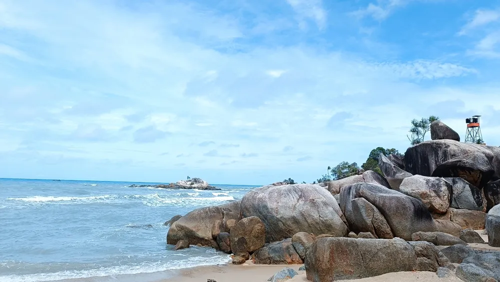 Pangkalpinang, Indonesia - March 02 2024: Beatiful beach with a background of large rocks, sea and blue sky