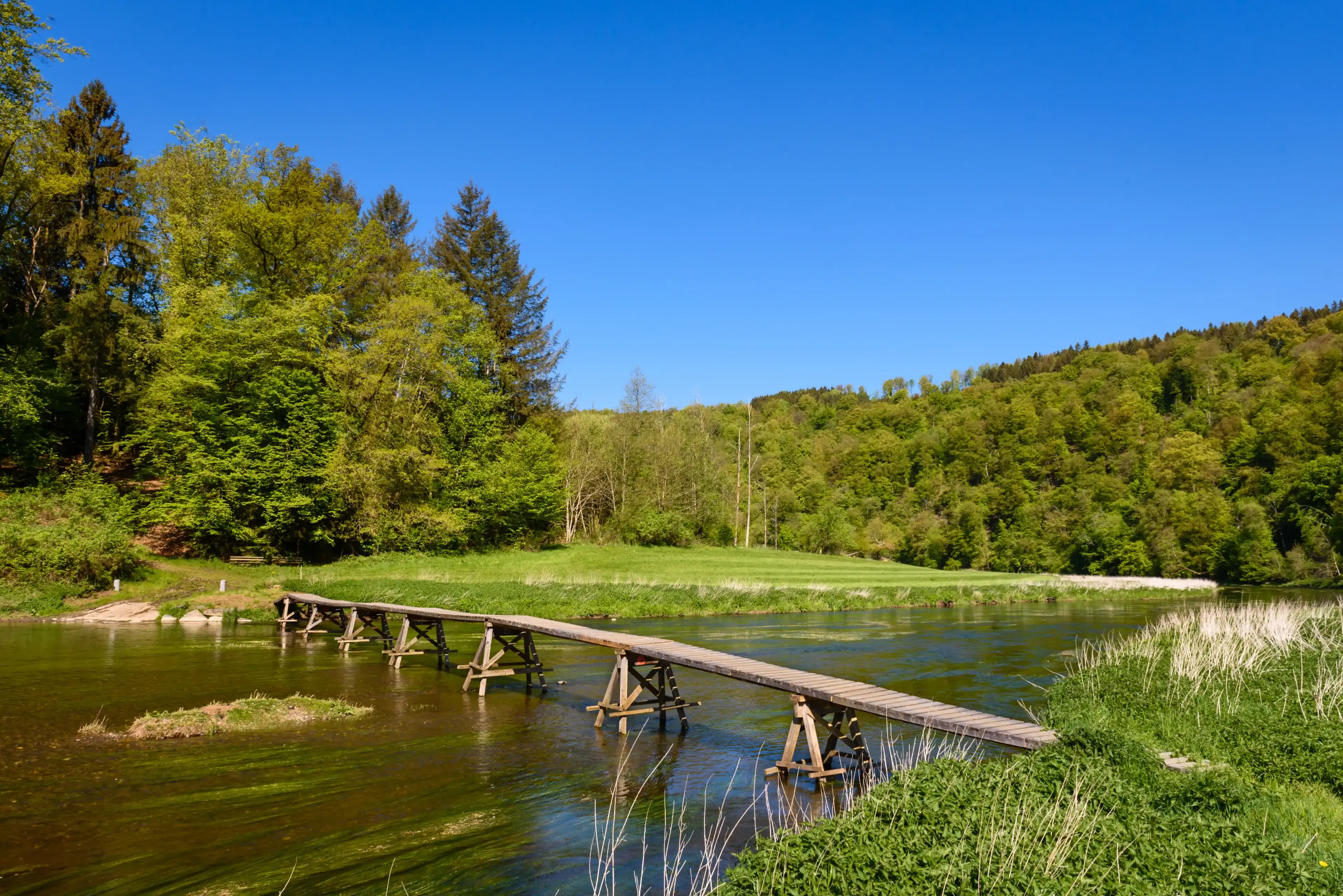 Wooden footbridge across Semois river in Cugnon (Bertrix), Luxembourg province, Ardennes region, Wallonia, Belgium. Wooden footbridge across Semois river in Cugnon (Bertrix), Luxembourg province, Ardennes region, Wallonia, Belgium.