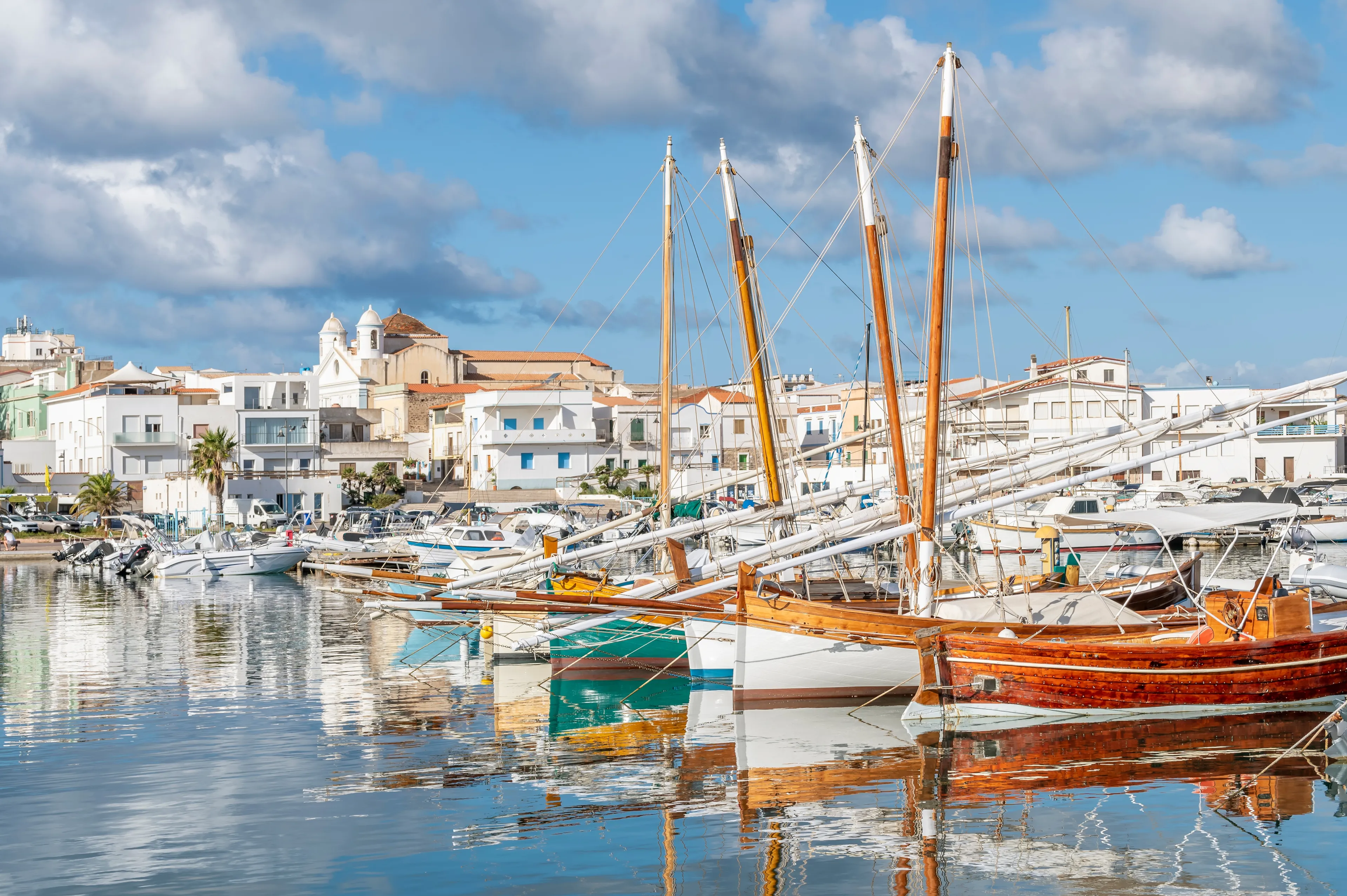 Colorful wooden boats are reflected in the water of the port of Calasetta, Sant'Antioco, Italy