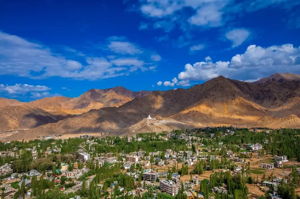 Leh, Ladakh India - 07 26 2024: A vibrant view of Leh, Ladakh, showcasing a leh city with shanti stupa, blend of lush greenery and arid mountains under a bright blue sky with scattered clouds. Leh, Ladakh India - 07 26 2024: A vibrant view of Leh, Ladakh, showcasing a leh city with shanti stupa, blend of lush greenery and arid mountains under a bright blue sky with scattered clouds.