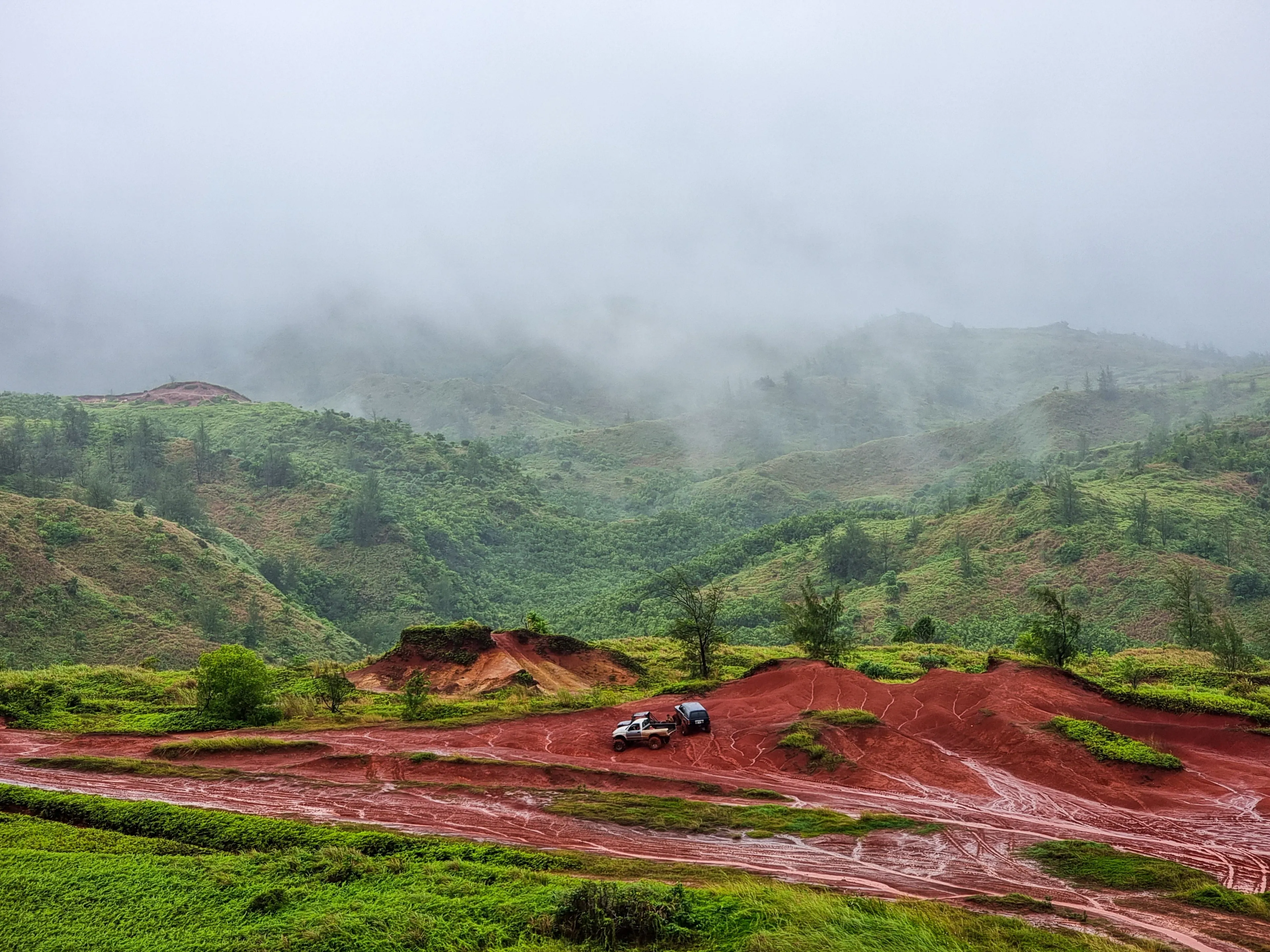 The three off-road cars in the valley surrounded by green mountains. Yona, Guam.