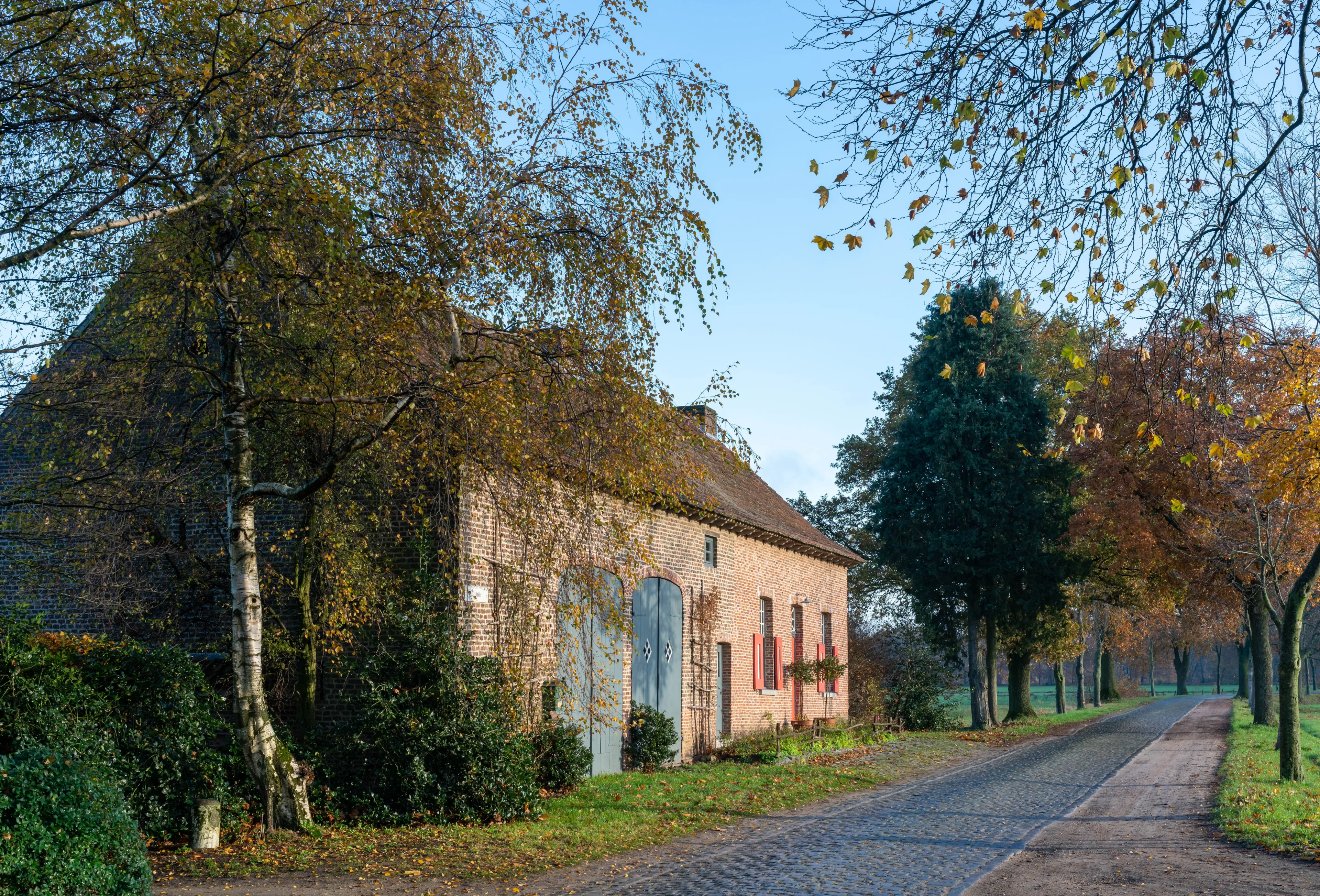 Renovated farm of six bays under gable roof with renewed cornice, cobbled road, Retie, Antwerp, Belgium