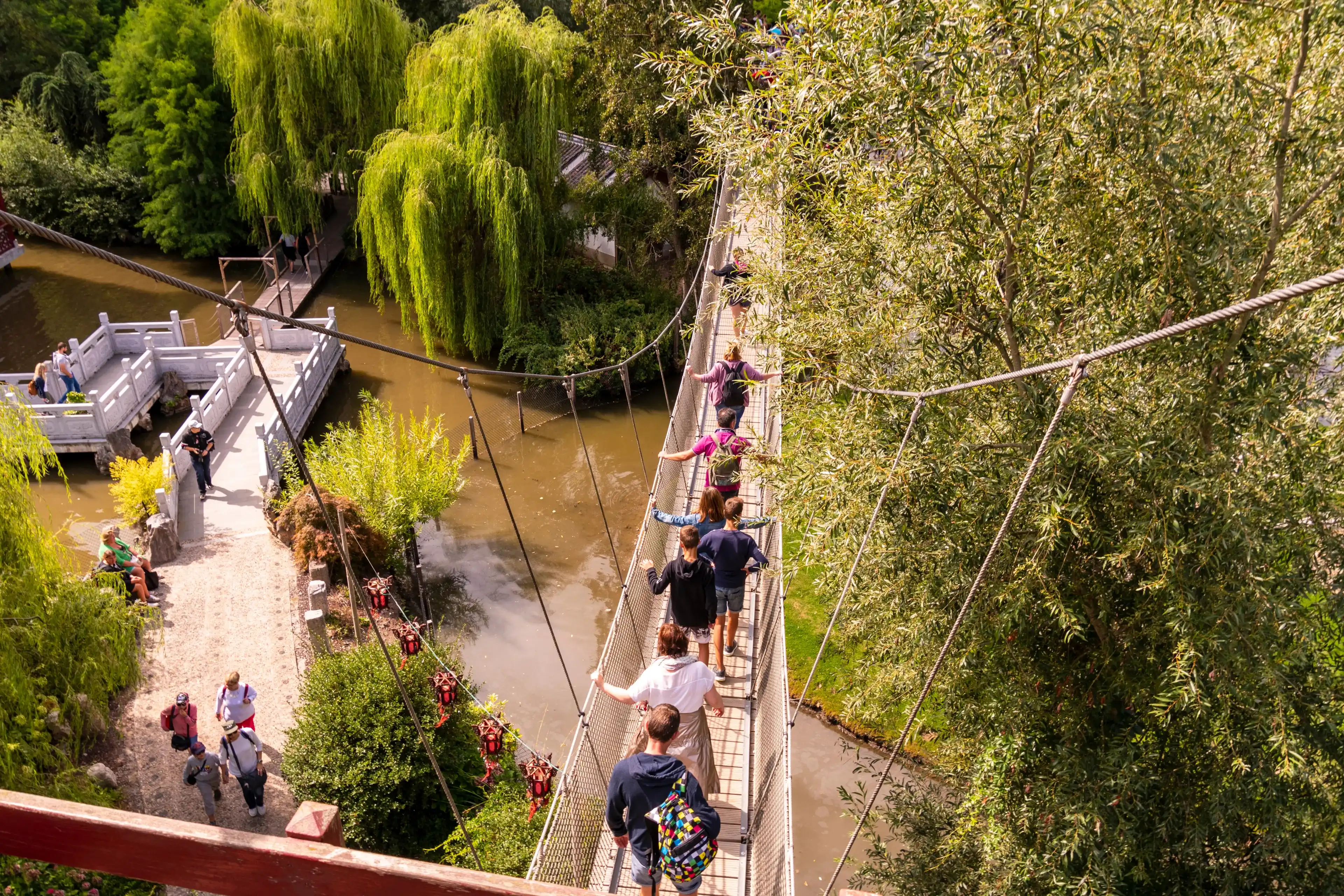 Bruggelette, Belgium - August 23, 2018: Theme Park Pairi Daiza. People walking across the hanging bridge Bruggelette, Belgium - August 23, 2018: Theme Park Pairi Daiza. People walking across the hanging bridge