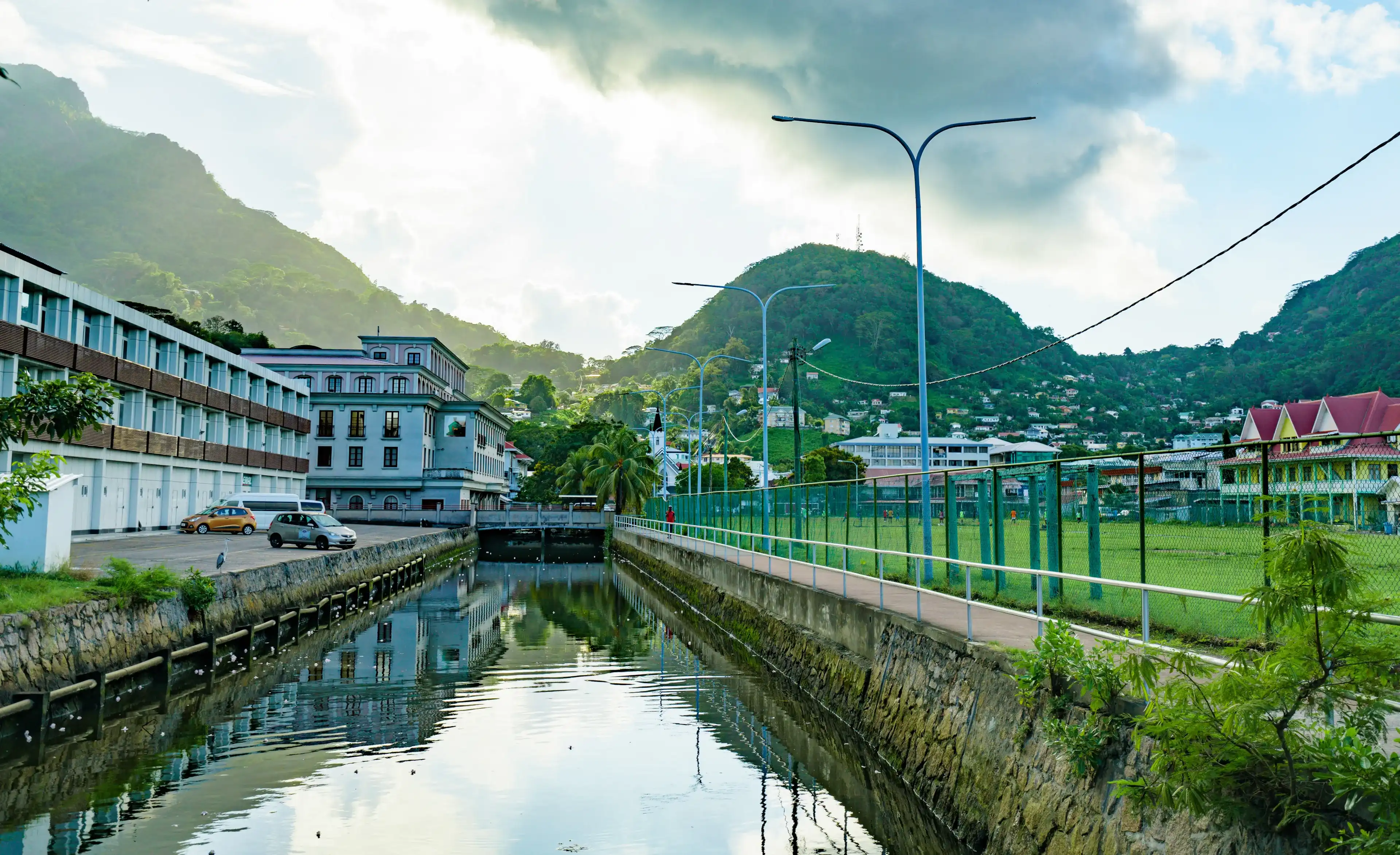 VICTORIA, SEYCHELLES - October 06, 2019: Part of the English River and a football stadium (Freedom Square) with a mountain and forest view. VICTORIA, SEYCHELLES - October 06, 2019: Part of the English River and a football stadium (Freedom Square) with a mountain and forest view.