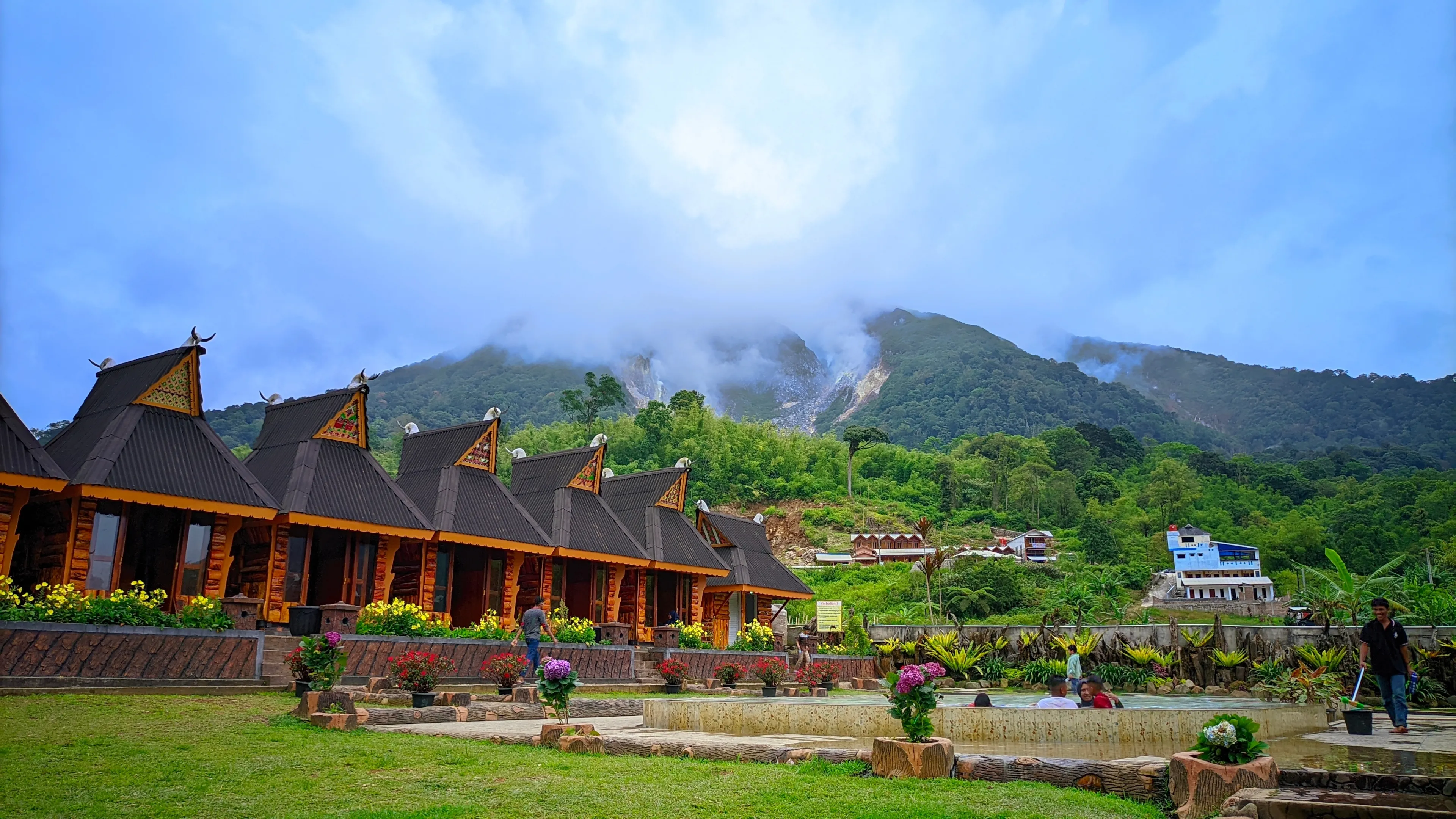 A beautiful and cool family vacation spot with a heated swimming pool, unique wooden houses and a cool mountain background. Berastagi, Indonesia July 23, 2023.