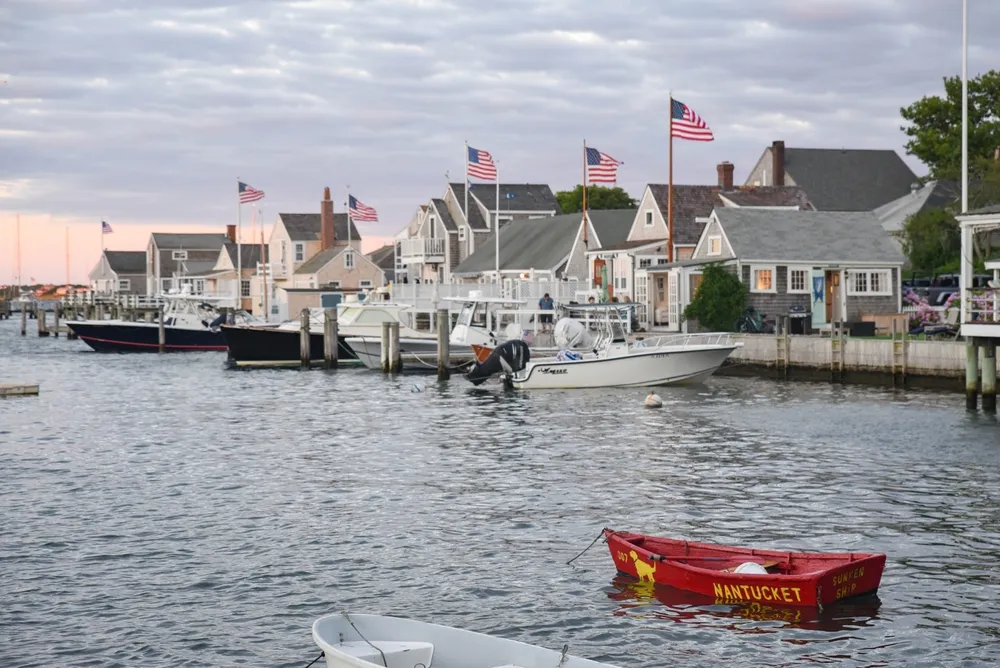 Nantucket, Massachusetts USA - July 6, 2022: A grey evening at the Easy Street Boat Basin in Nantucket harbor overlooking shingled cottages, boats, and six American Flags flying proudly