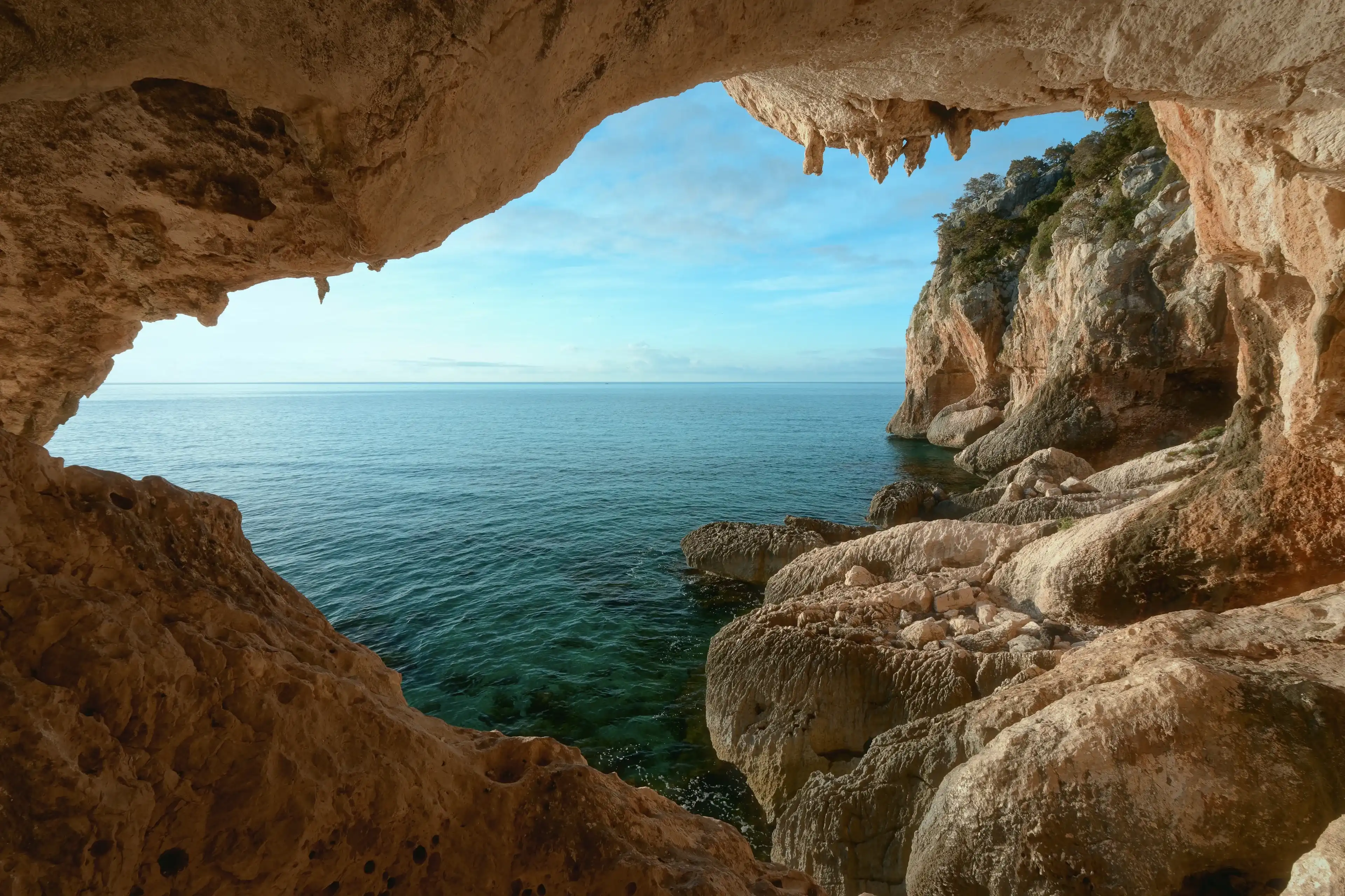The view from the cave to rocky coast near Cala Gonone, Sardinia. Italy. Vacation travel holiday banner, summer mood. The view from the cave to rocky coast near Cala Gonone, Sardinia. Italy. Vacation travel holiday banner, summer mood.