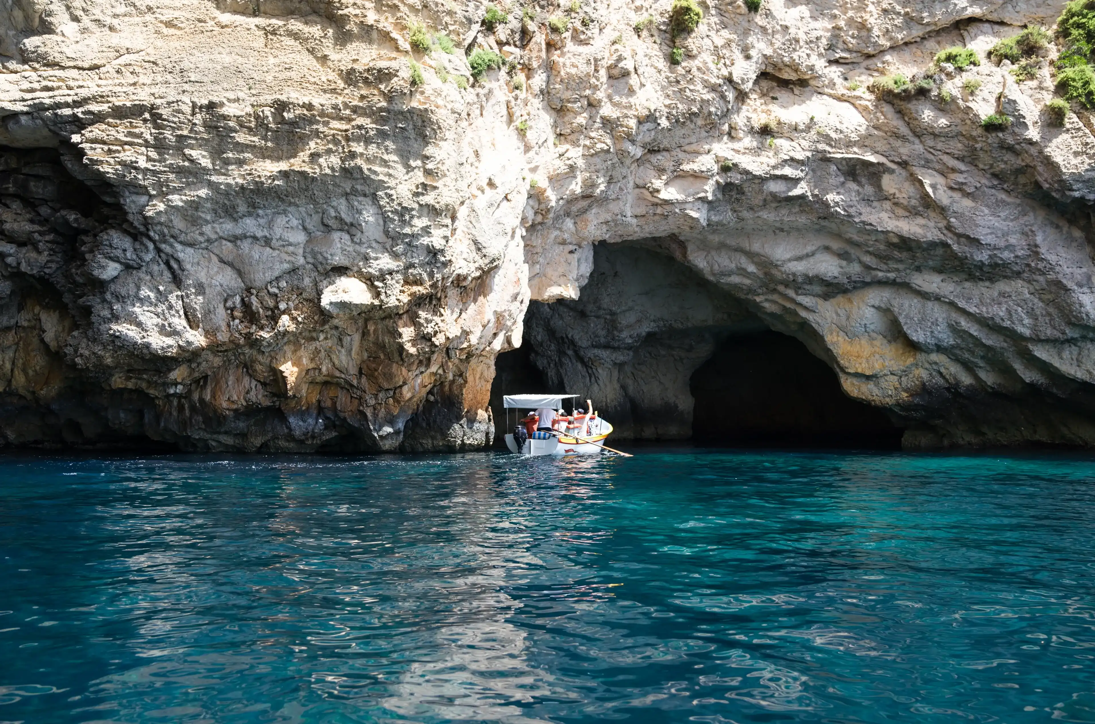Il-Qrendi, Malta - July 18 2023: Magnificent scenery of Blue Grotto sea caverns from sea level close to Wied iz-Zurrieq. Hot summer day. Boat with tourists. Il-Qrendi, Malta - July 18 2023: Magnificent scenery of Blue Grotto sea caverns from sea level close to Wied iz-Zurrieq. Hot summer day. Boat with tourists.
