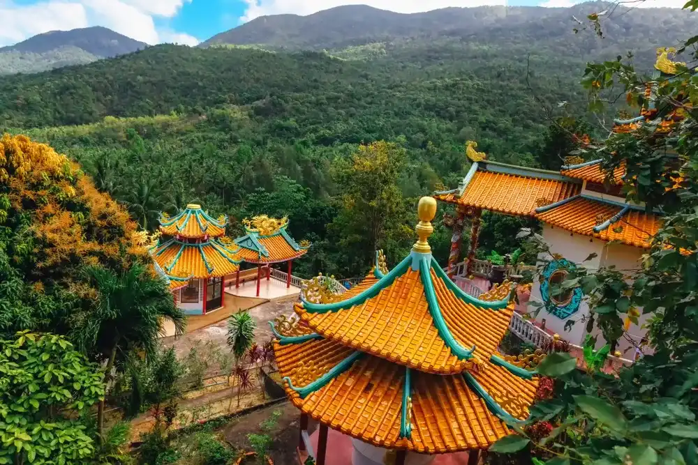 Beautiful view of Chinese Sangthom Temple of the Goddess of Mercy Shrine in Chaloklum, Ko Pha Ngan, Thailand Showing the ornate, orange roof of the main pagoda and the surrounding jungle. Beautiful view of Chinese Sangthom Temple of the Goddess of Mercy Shrine in Chaloklum, Ko Pha Ngan, Thailand Showing the ornate, orange roof of the main pagoda and the surrounding jungle.
