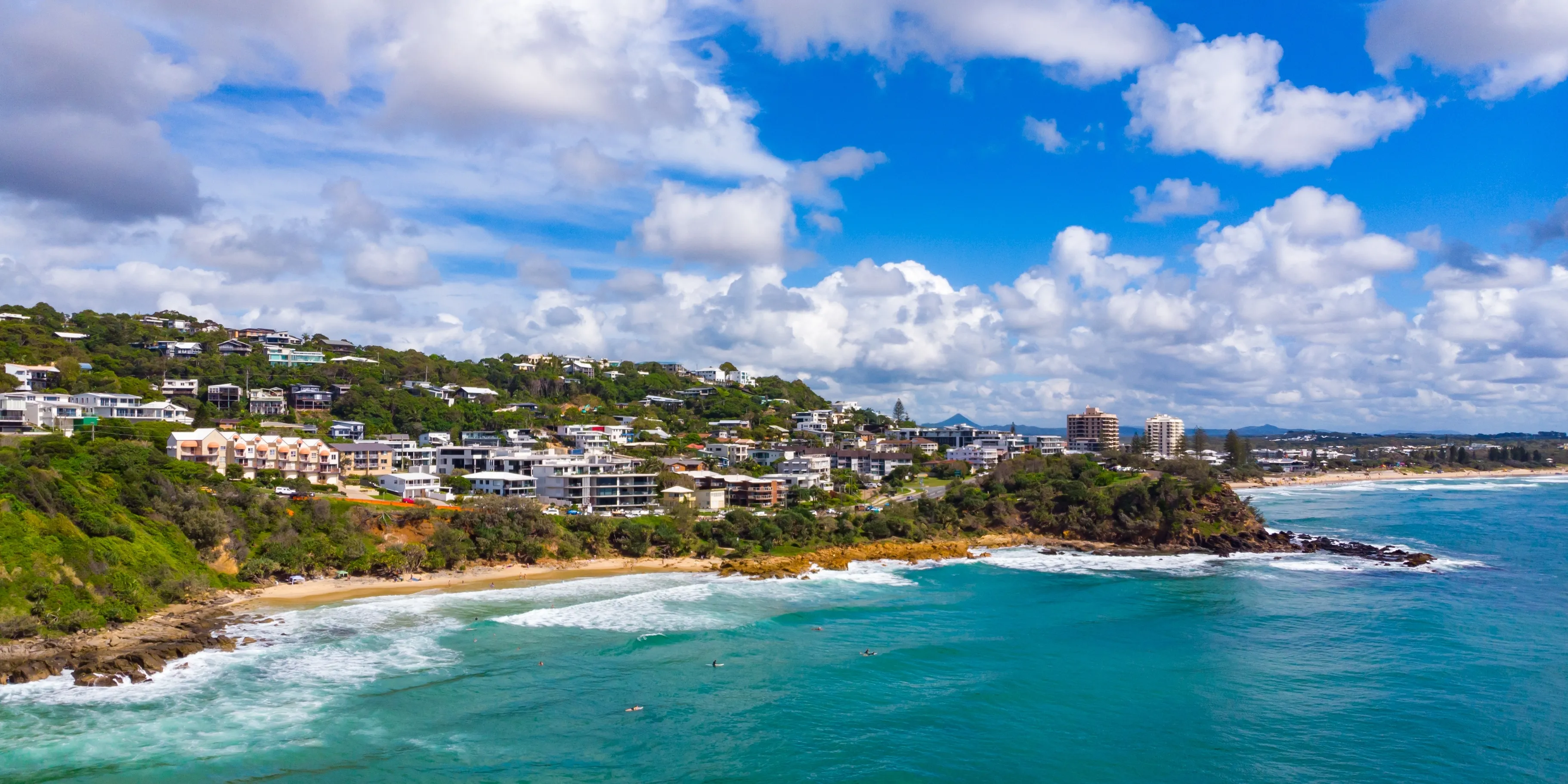 Aerial, drone view of the spectacular Coolum Beach and Sunshine Coast city near Brisbane. Beautiful buildings on the cliffs and golden sand beaches at sunrise. Landscape of Queensland, Australia 