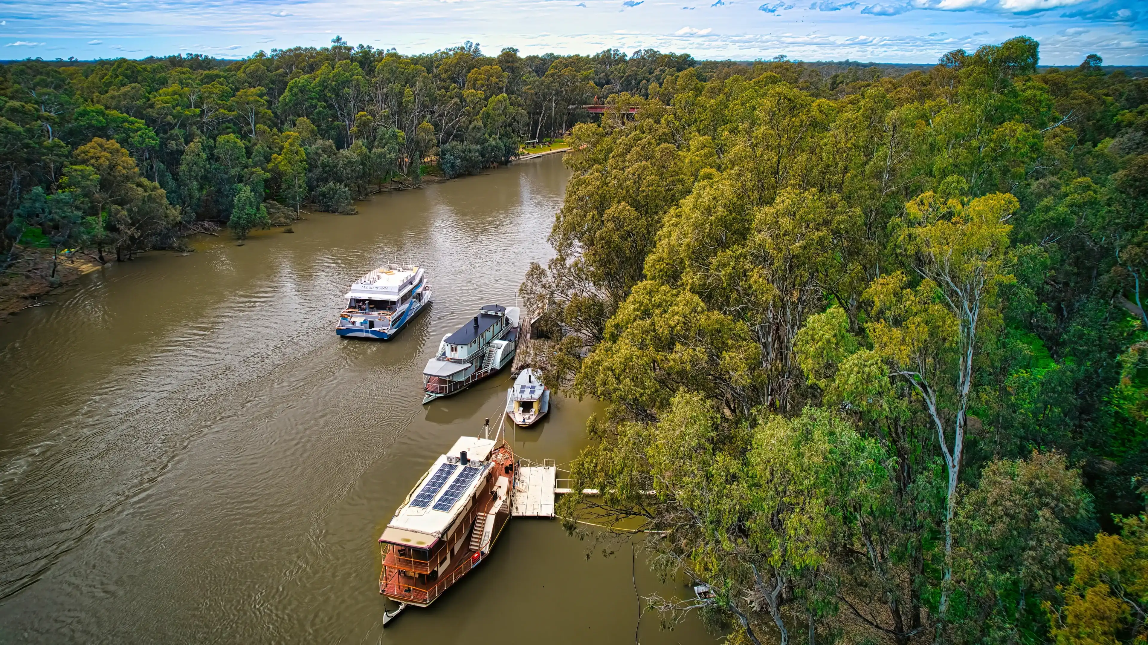 Echuca, Victoria, Australia - 12 August 2022: A cruising boat passing some paddle boats on the Murray River at Echuca Victoria Echuca, Victoria, Australia - 12 August 2022: A cruising boat passing some paddle boats on the Murray River at Echuca Victoria