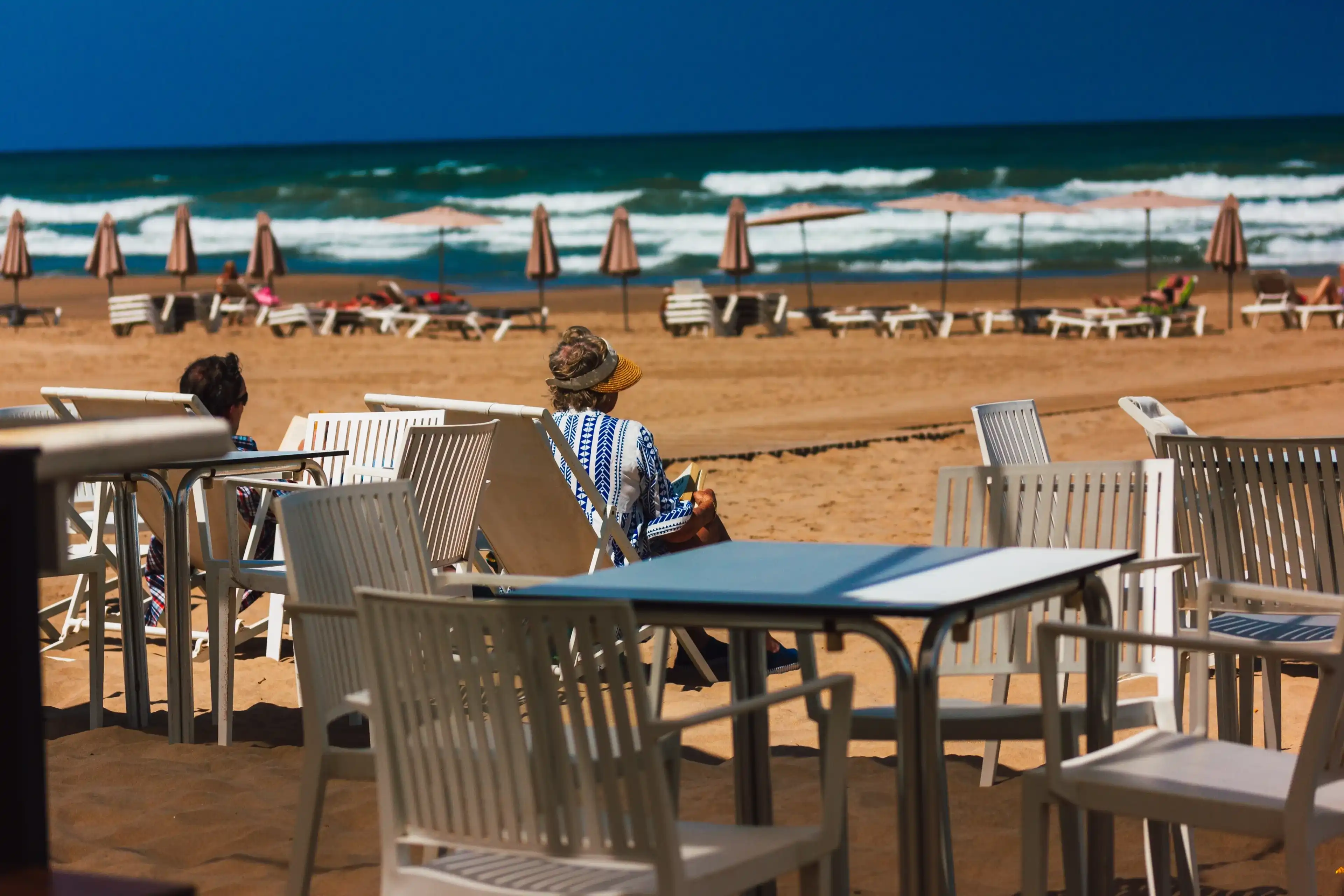 Gandia, Spain. June 1, 2024 Scene of city beach with people relaxing on the beach, ocean in summer. Vacation on the coast of the resort. Cafe terrace. Gandia, Spain. June 1, 2024 Scene of city beach with people relaxing on the beach, ocean in summer. Vacation on the coast of the resort. Cafe terrace.