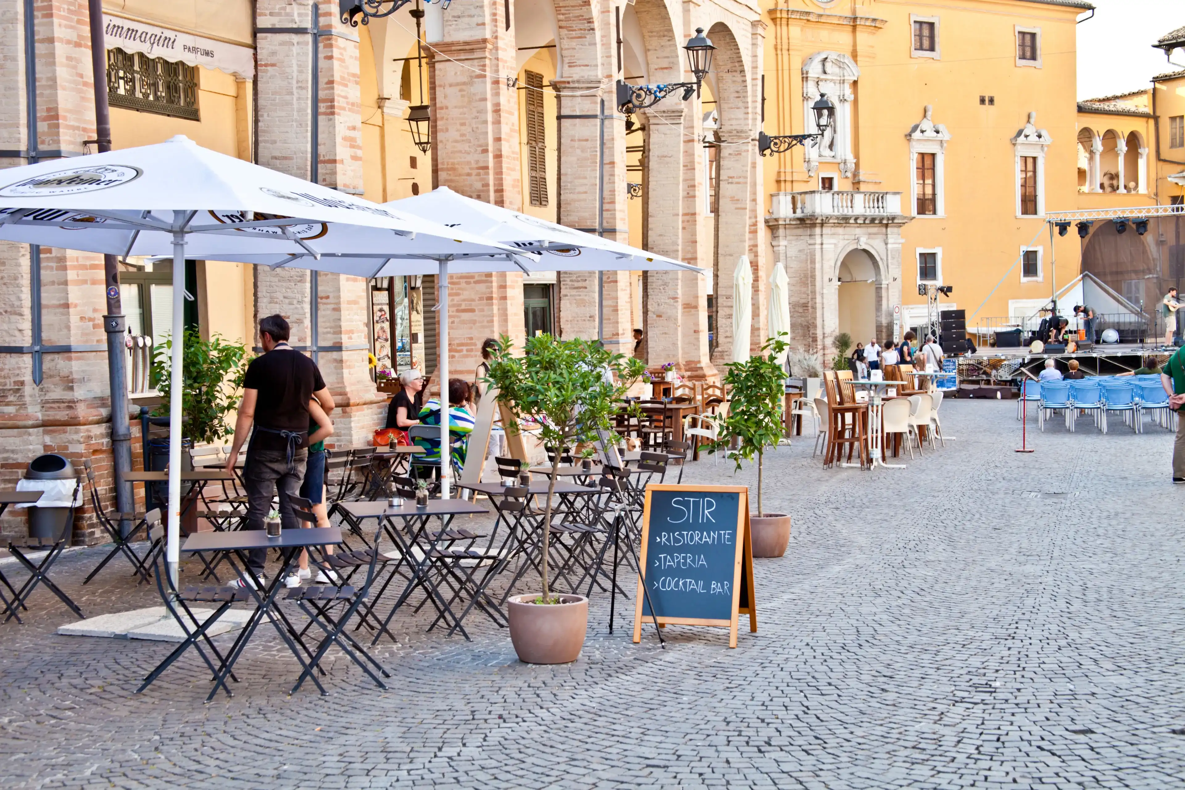 Fermo, Italy - June 23, 2019: People enjoying summer day and food at outdoor restaurant and resting, Piazza del Popolo, Fermo, Italy Fermo, Italy - June 23, 2019: People enjoying summer day and food at outdoor restaurant and resting, Piazza del Popolo, Fermo, Italy