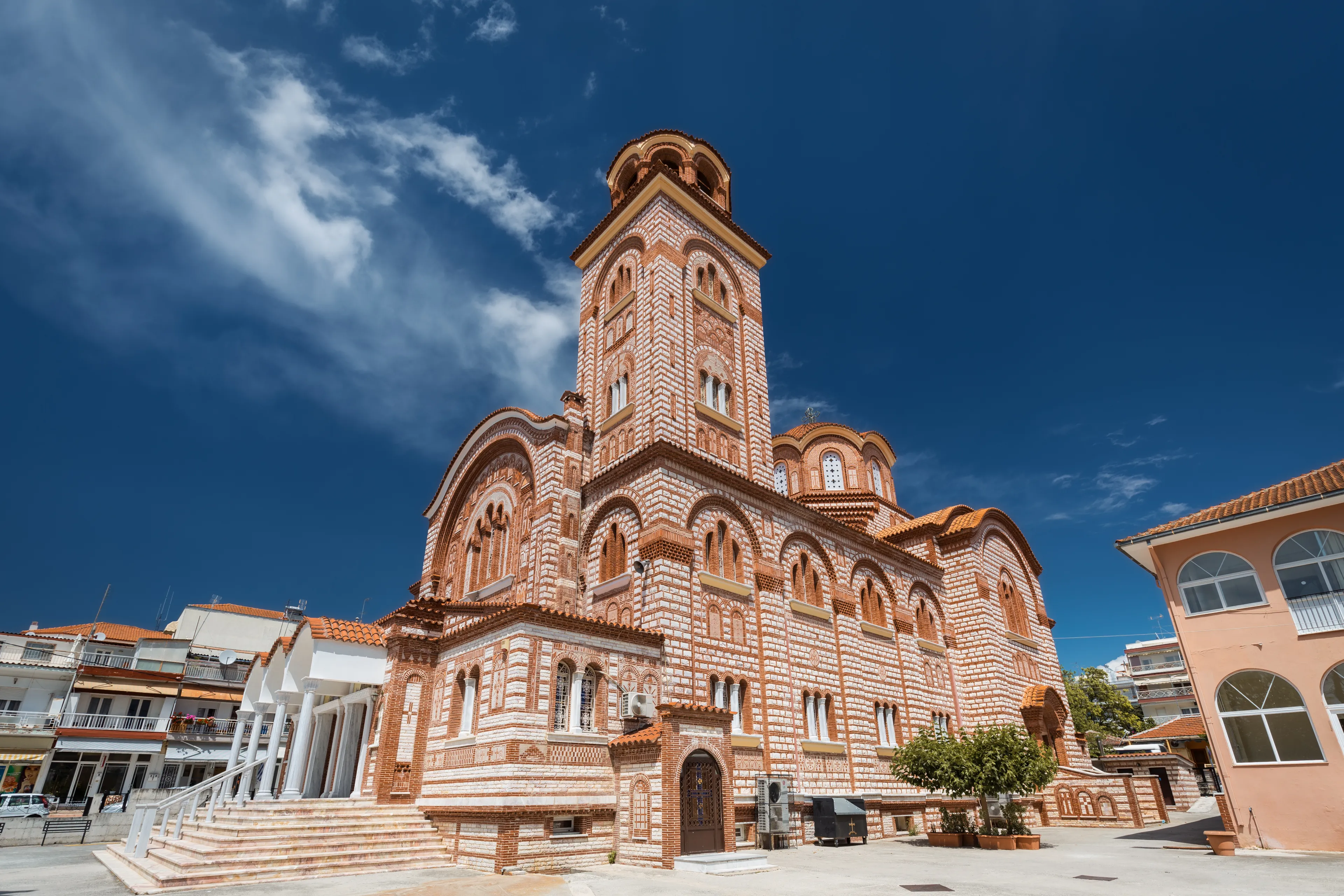 Nea Kallikrateia, Greece - MAY 28 2021: Giant Greek Orthodox cathedral against vivid blue sky in a small Mediterranean town near Thessaloniki