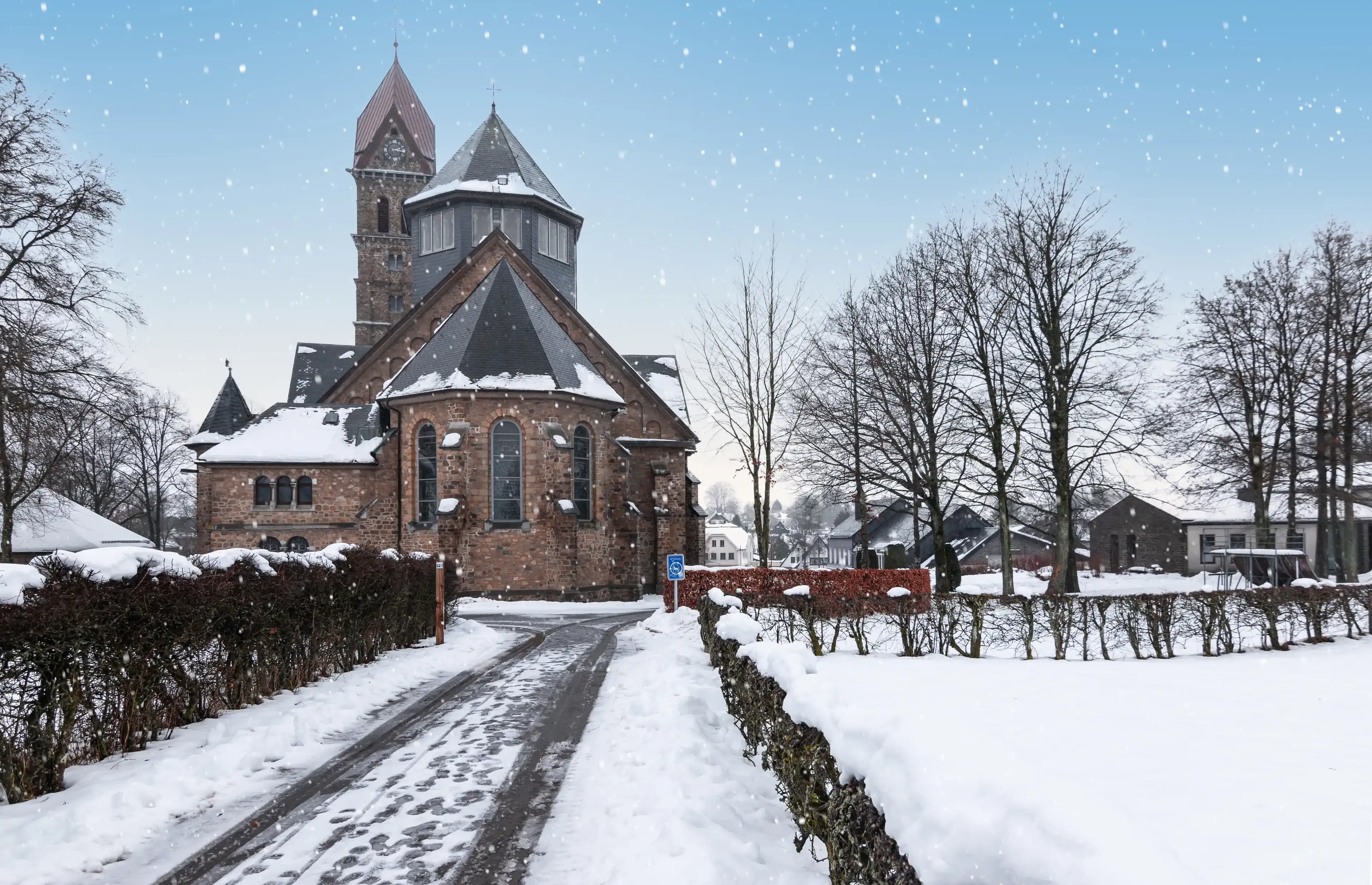 Catholic parish church and snowy street in Butgenbach, Ardennes, Belgium. Catholic parish church and snowy street in Butgenbach, Ardennes, Belgium.