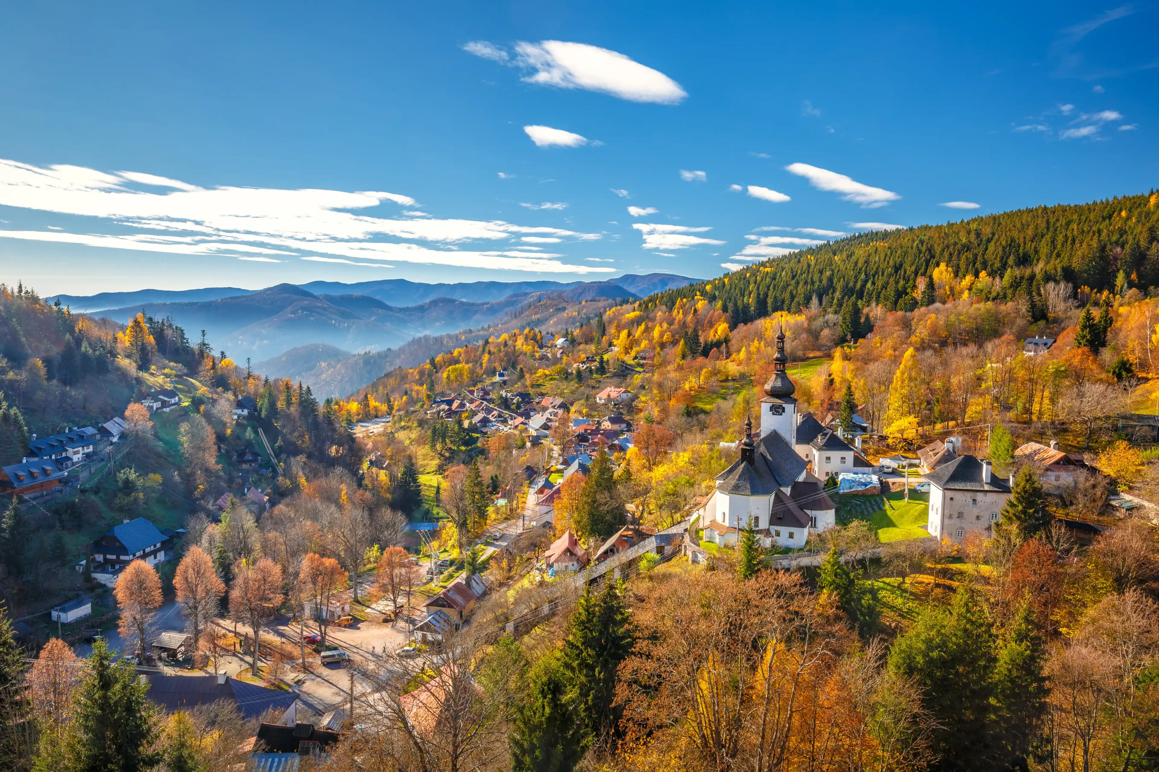 The Spania Dolina village with church and historic buildings in valley of autumn landscape, Slovakia, Europe. The Spania Dolina village with church and historic buildings in valley of autumn landscape, Slovakia, Europe.