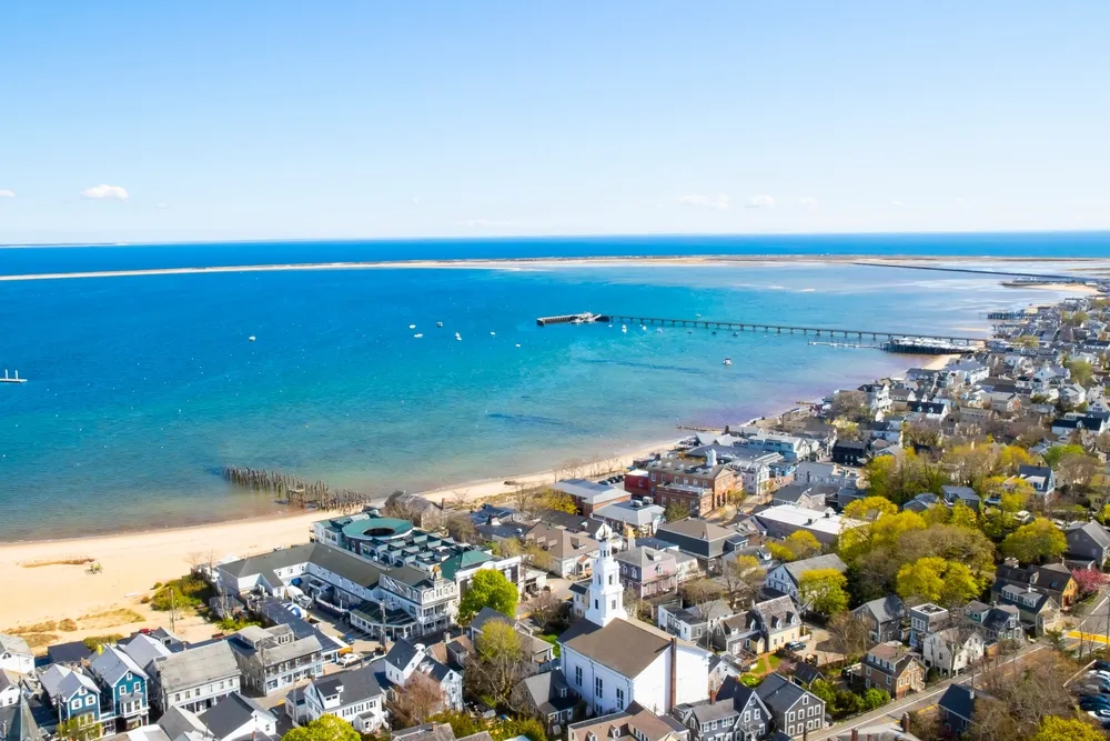 Provincetown, Massachusetts, United States - May 3th, 2023 : View of the harbour located next to the buildings of Provincetown. There is a blue sky. A sandy beach is located along the shore.