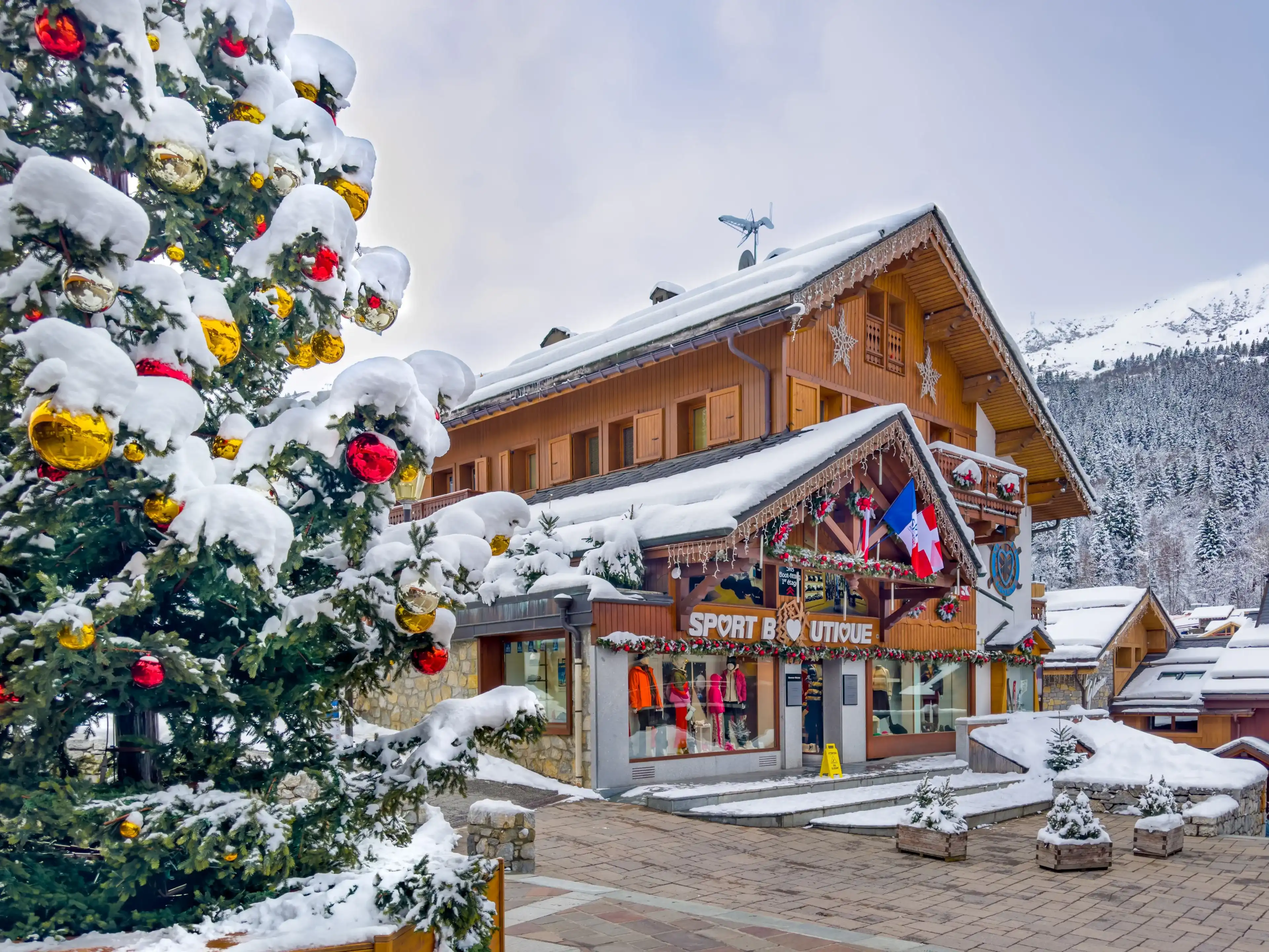 COURCHEVEL - MERIBEL, FRANCE - JANUARY 15, 2023 : Christmas tree and wood chalets in Meribel, France. COURCHEVEL - MERIBEL, FRANCE - JANUARY 15, 2023 : Christmas tree and wood chalets in Meribel, France.