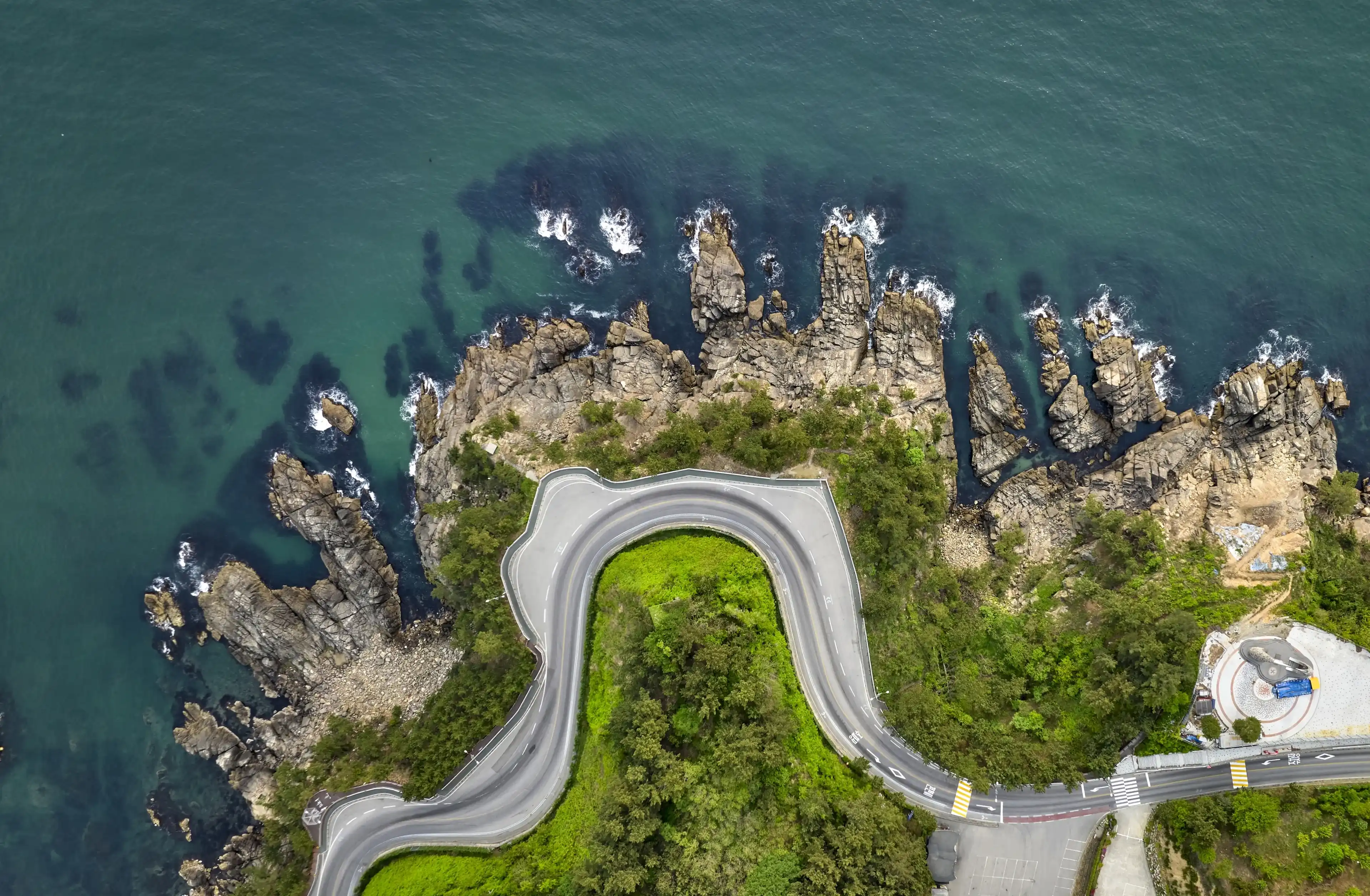 Aerial and top angle view of curved road with Tower of Hope besides rocks and sea at Gyo-dong of Samcheok-si, South Korea Aerial and top angle view of curved road with Tower of Hope besides rocks and sea at Gyo-dong of Samcheok-si, South Korea