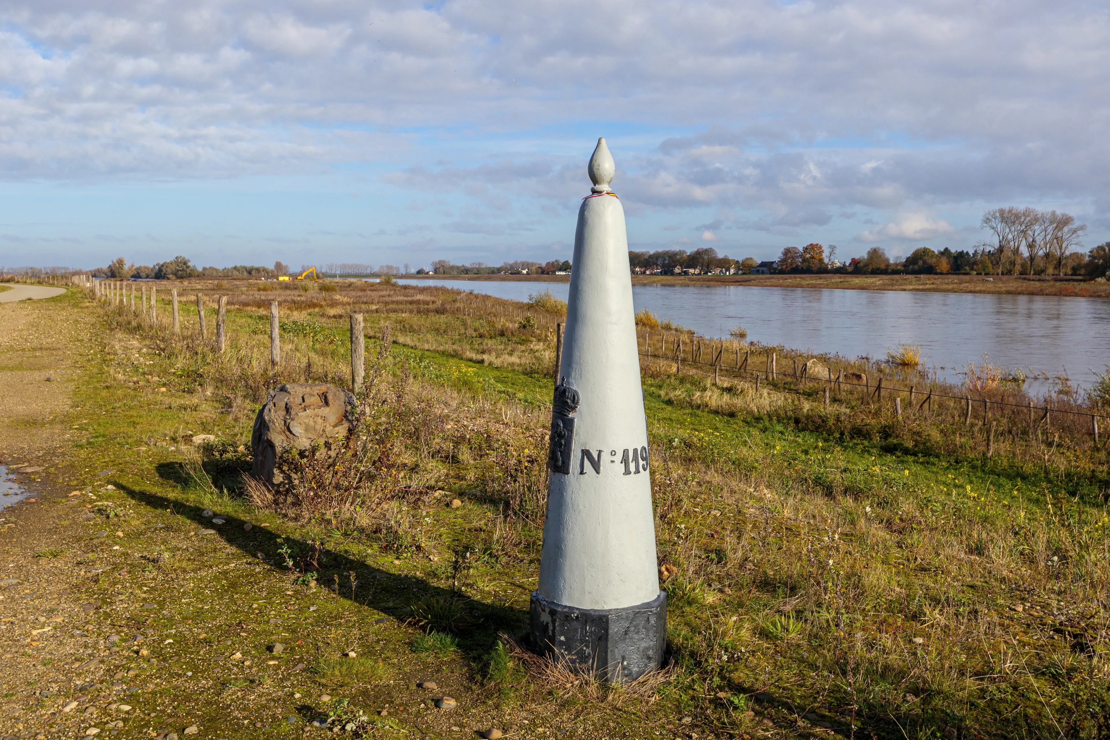 Belgian nature reserve De Wissen Maasvallei with a border marker between Belgium and Holland, Maas river in misty background, sunny autumn day in Dilsen-Stokkem, Belgium. Treaty of Maastricht of 1843