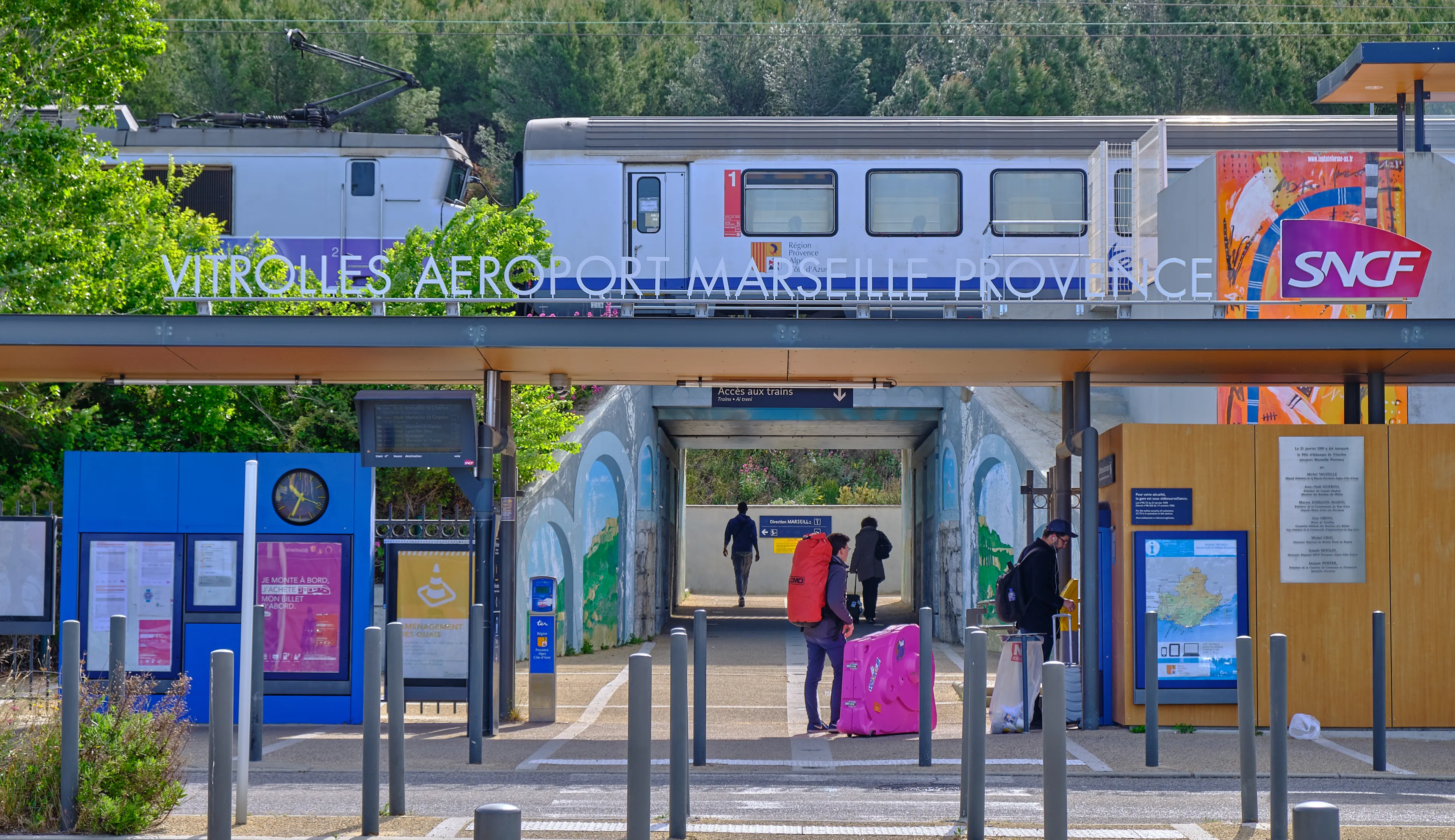 Vitrolles, France, April 28, 2019 : Passenger entering the train station serving the Marseille airport, with a TER train in station on elevated tracks