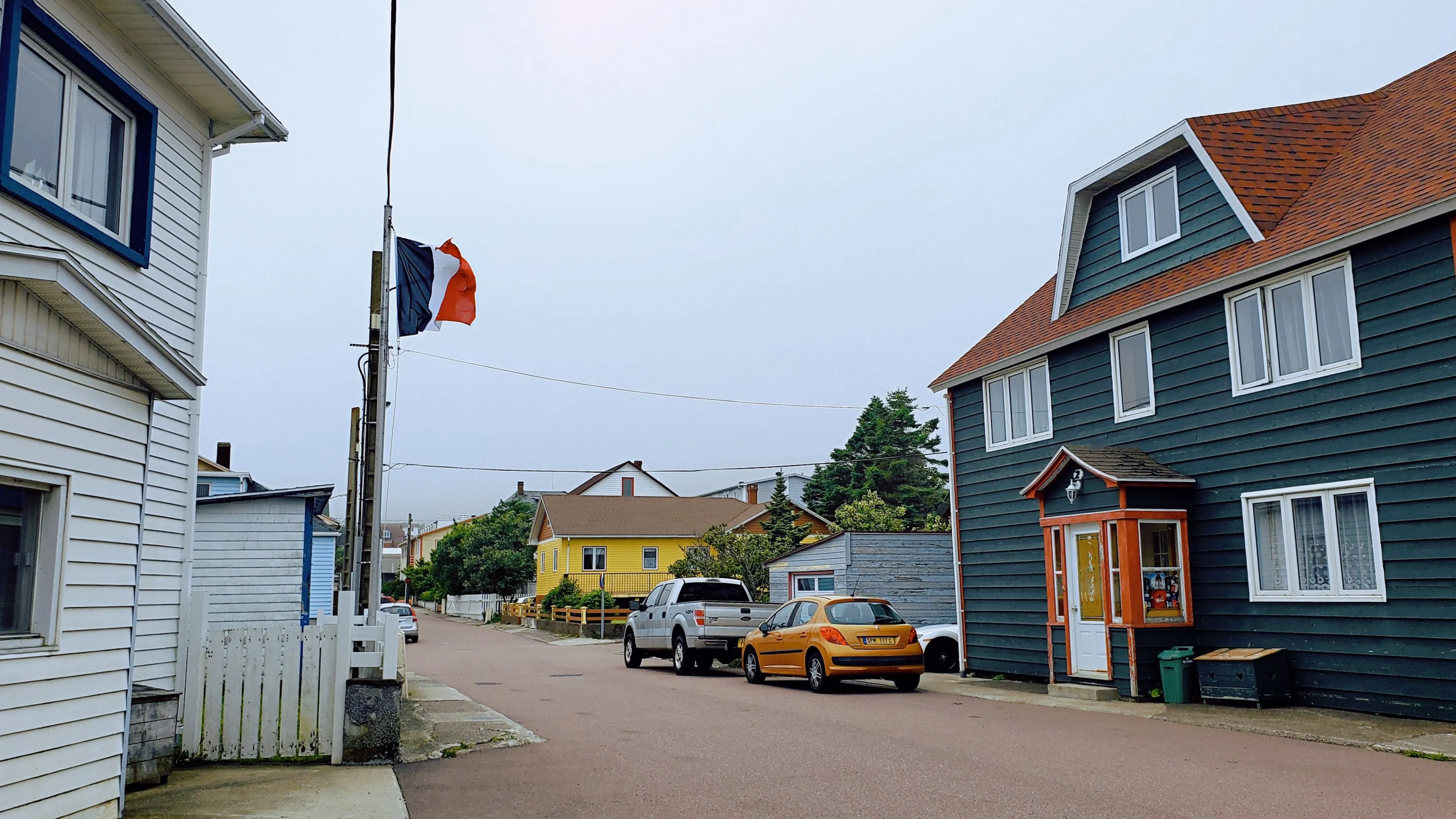 SAINT PIERRE AND MIQUELON, FR - Jun 28, 2022: An empty street with colorful buildings and a couple of parked cars. Saint Pierre and Miquelon.