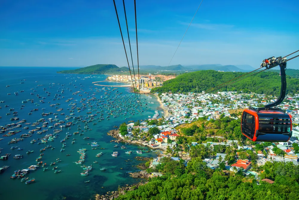 The longest cable car situated on the Phu Quoc Island in South Vietnam and below is traditional fishermen boats lined in the harbor of Duong Dong town in the popular Hon Thom island. Travel concept.