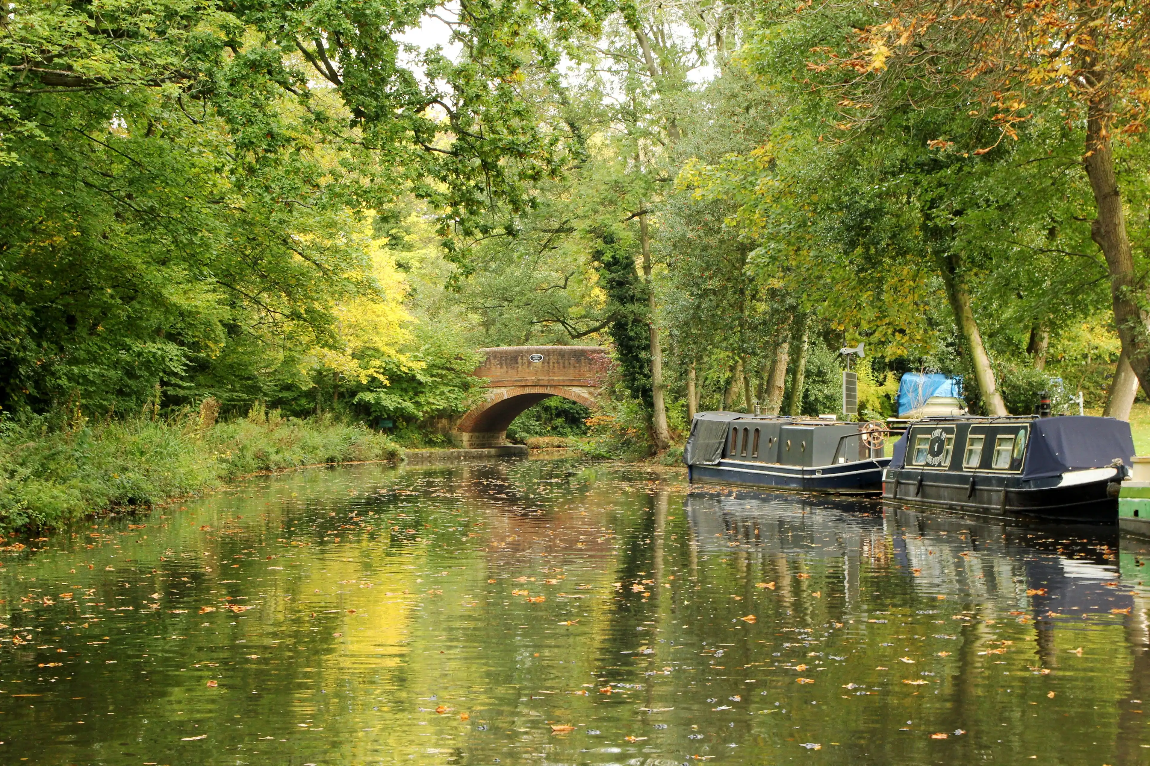 Basingstoke Canal, near to to Farnboroigh, United Kingdom. Narrow boats used for canal navigation and old bridge Basingstoke Canal, near to to Farnboroigh, United Kingdom. Narrow boats used for canal navigation and old bridge