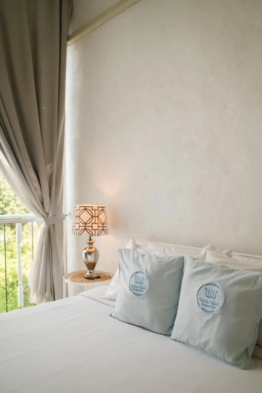 Bed in White Wall Riverfront Hotel